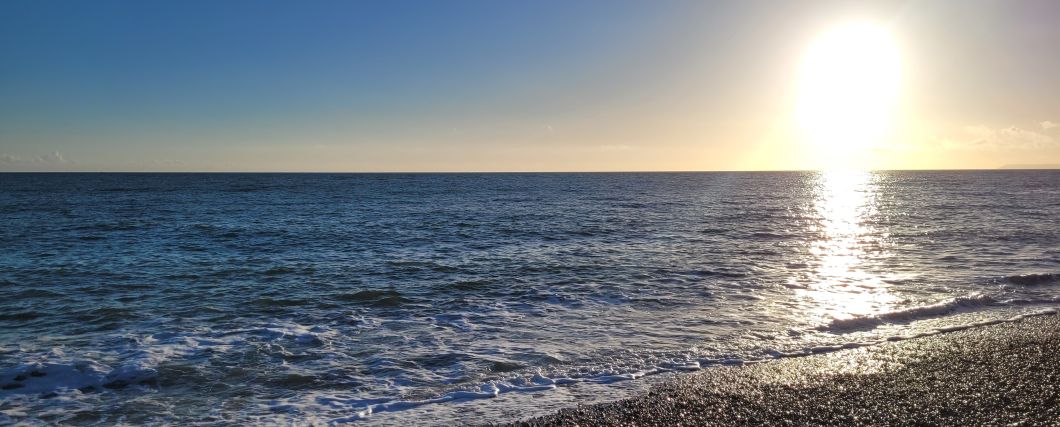 A view from Hastings beach out into the English Channel, with the sun low in the sky