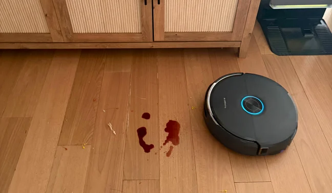 Narwal Flow 2 robot vacuum mopping up wine spill in front of credenza and dock