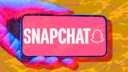 Hand holding phone with Snapchat logo against abstract background