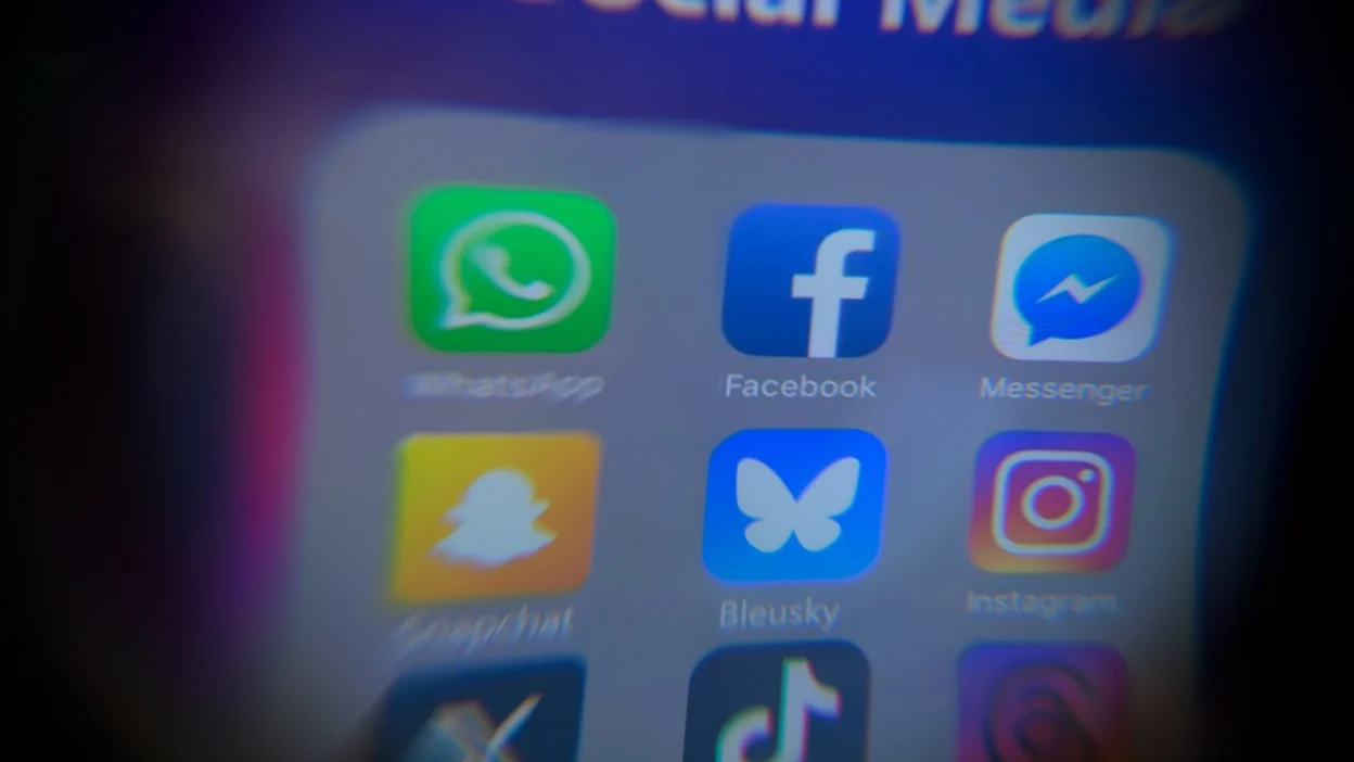 blurry social media icons on iphone screen with Bluesky app in center