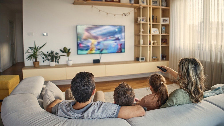 A family watching a wall-mounted TV in a modern living room.