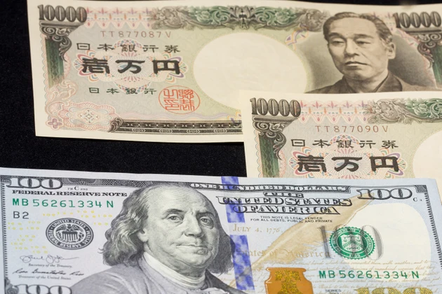 US $100 bill and two 10,000 JPY bills on solid black background