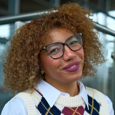 A woman with curly hair …g and tilting her head.