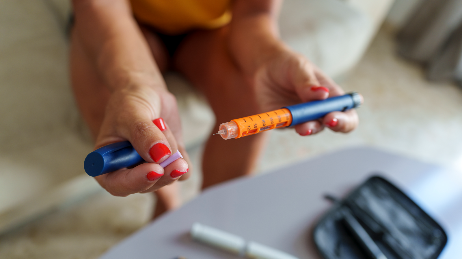 Unrecognizable middle-aged woman preparing an insulin pen to inject herself with a dose.