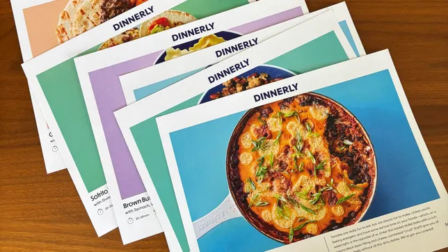 Dinnerly recipe cards fanned out on a wood tabletop.