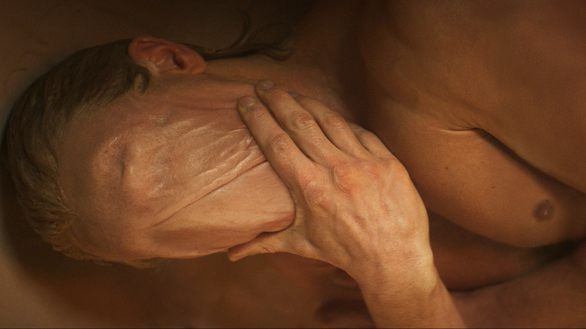Matt Hagen moulding the skin across his entire face while lying in a bathtub in Clayface