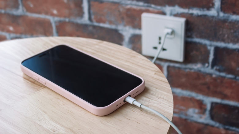 An iPhone connected to a USB wall socket.