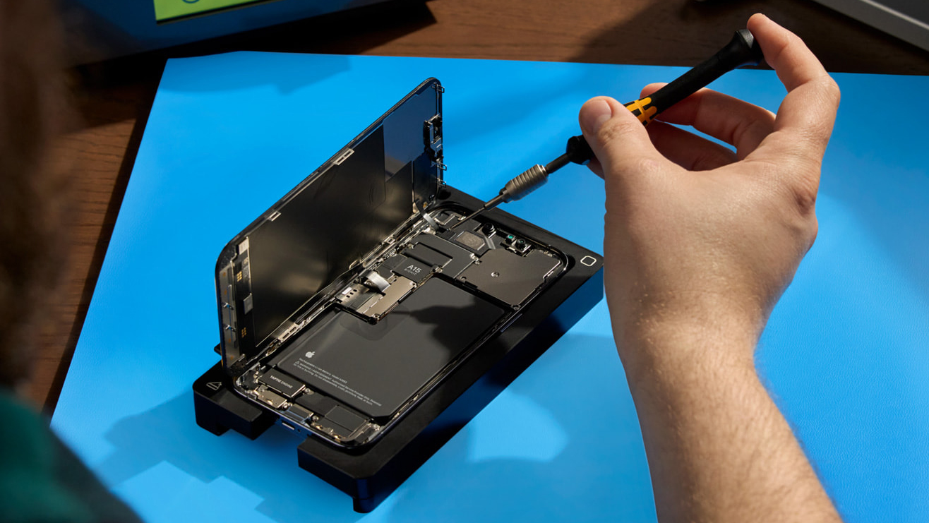 A man doing an Apple Self Service Repair on an iPhone resting on a blue mat