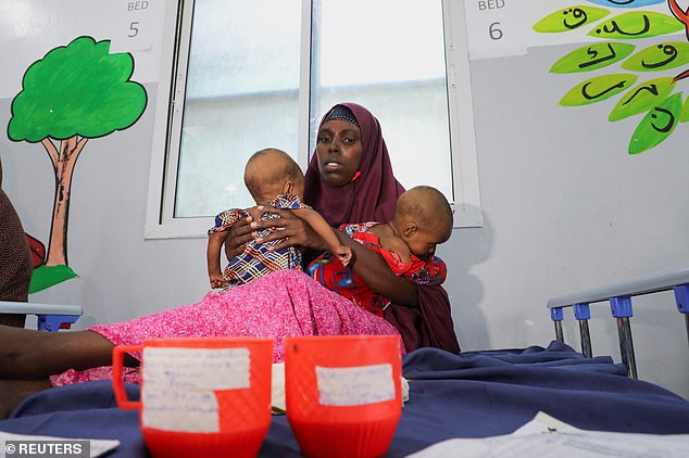 An Internally displaced Somali woman holds her malnourished twin children inside the pediatric ward at the Daynile hospital, as shortages of lifesaving therapeutic foods caused by shipping disruptions due to the Iran war have forced clinics treating severely malnourished children to turn away patients and ration supplies in drought-hit Somalia, in Daynile district of Mogadishu, Somalia April 20, 2026. REUTERS/Feisal Omar