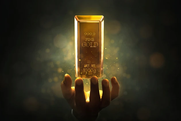 Businessman hands holding flying shiny floating gold bar with magic glitter sparkle effect on dark background
