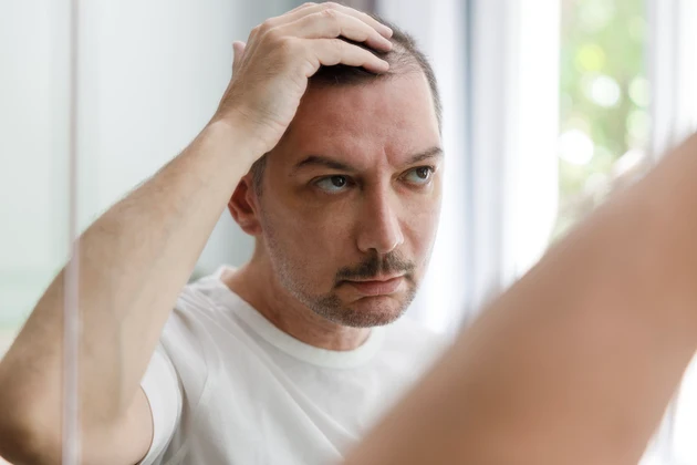 Middle aged man checking his bald spots in the mirror