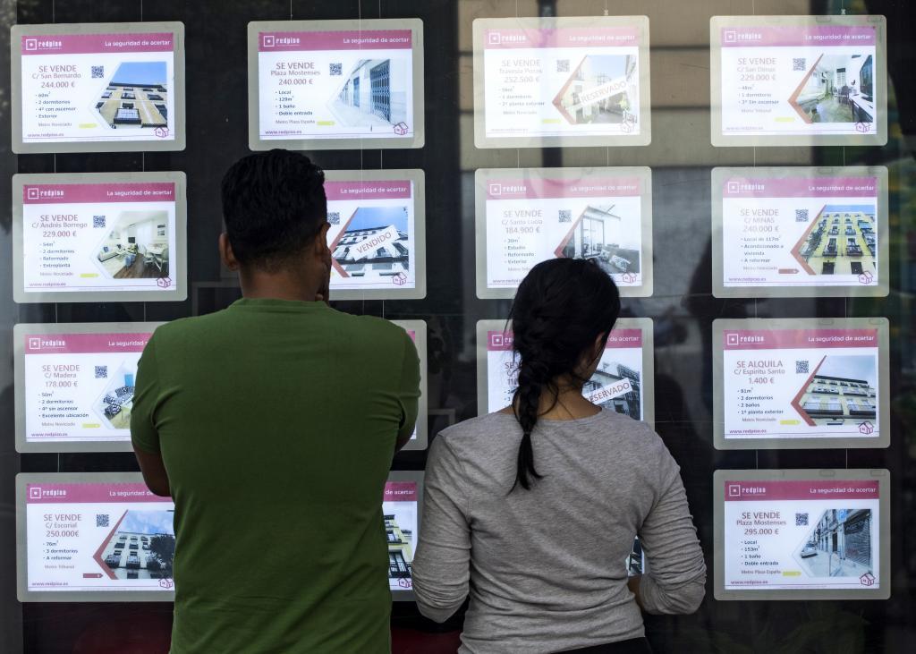 Dos j�venes observan los anuncios de pisos de una inmobiliaria en las calles de Madrid.