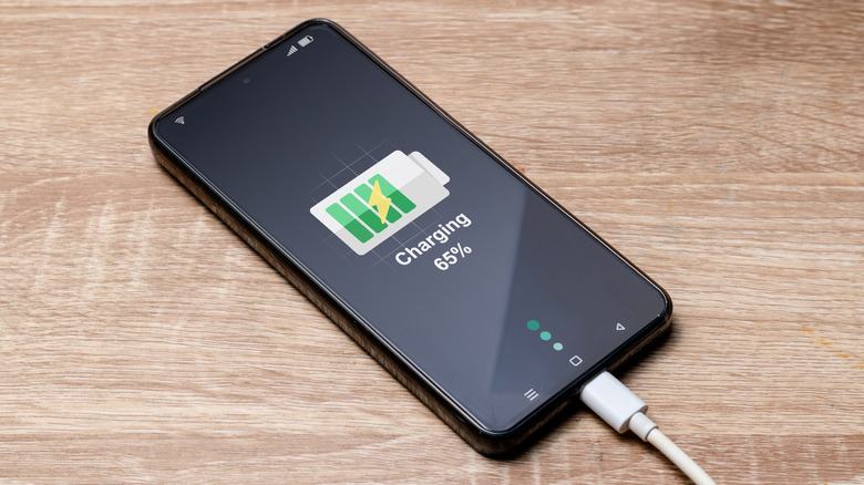 A smartphone being charged on a wooden table