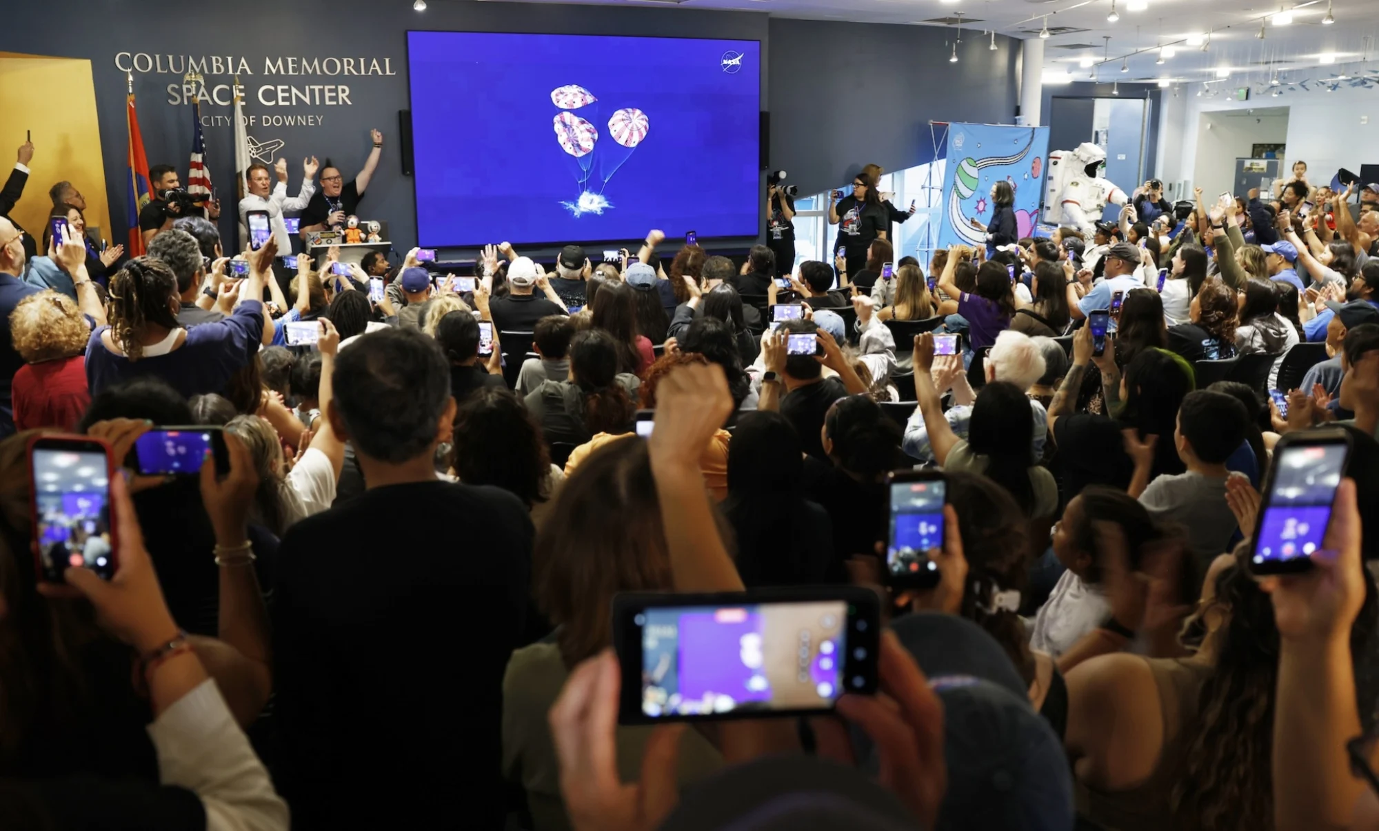 People celebrate as the Artemis II mission concludes with a successful splashdown during a watch party