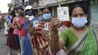 Women are holding up their Voter ID card. Women are holding up their Voter ID card.