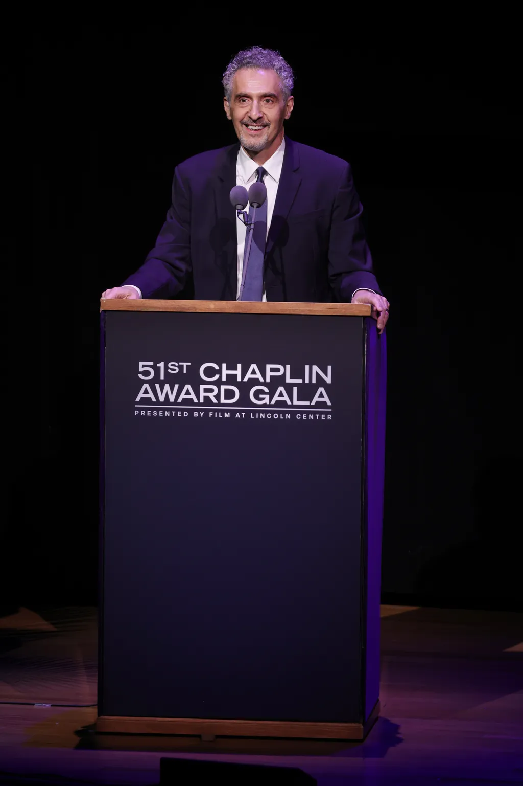 Image may contain John Turturro Crowd Person Audience Accessories Formal Wear Tie Adult Podium Speech and Face