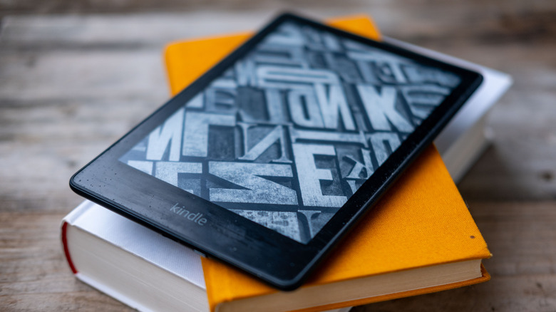Kindle e-reader on stack paper books