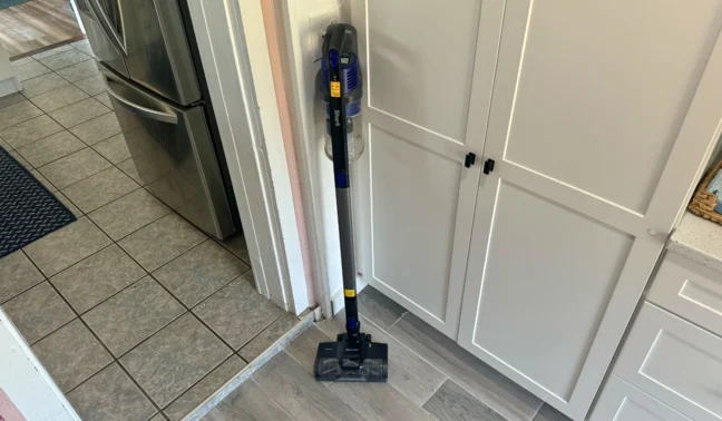 Shark cordless vacuum leaning against wall in kitchen