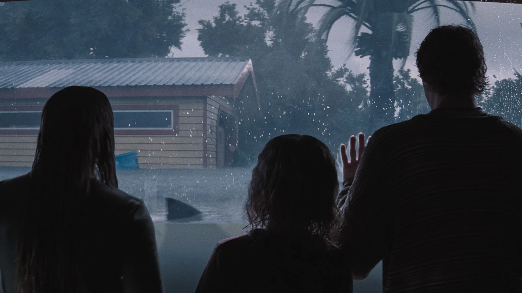 Three kids stand behind glass as a shark sails past in "Thrash."