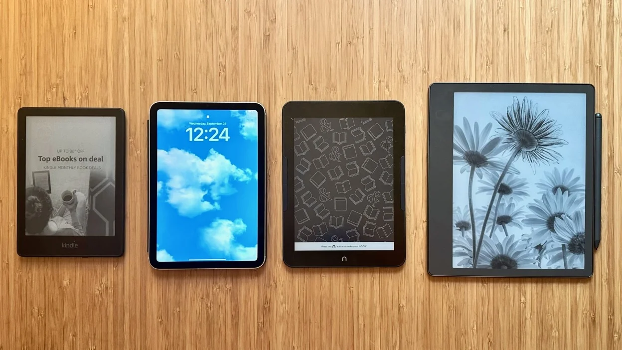 A Kindle Paperwhite, an iPad Mini, a Nook GlowLight 4 Plus, and a Kindle Scribe on a wooden table