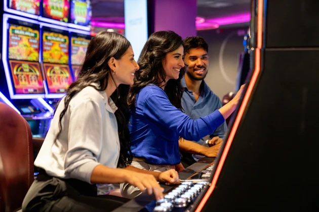 Happy group of friends at a casino playing on the slot machines