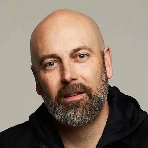 A shaven-headed man with…d slightly to one side.