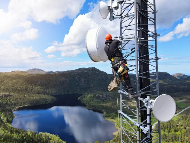 Engineer utility infrastructure worker at big steel mast working with radio link, microwave, 4G, 5G