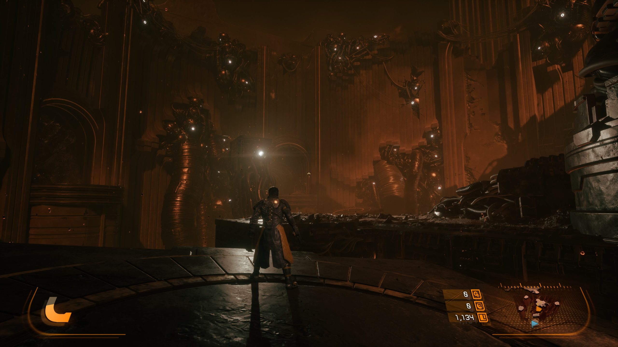 A character in Saros on a detailed armor stands in a dark, industrial environment with mechanical structures, viewed from a third-person perspective with on-screen elements showing a health bar and map.