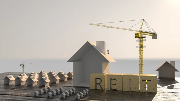 Concept image of Business Acronym REIT as Real Estate Investment Trust. Many houses and construction cranes. 3d rendering