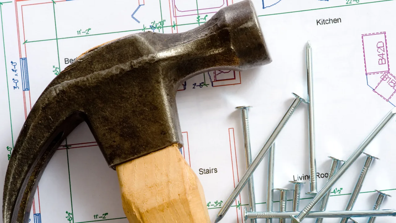 A hammer and nails lying on top of architect plans.