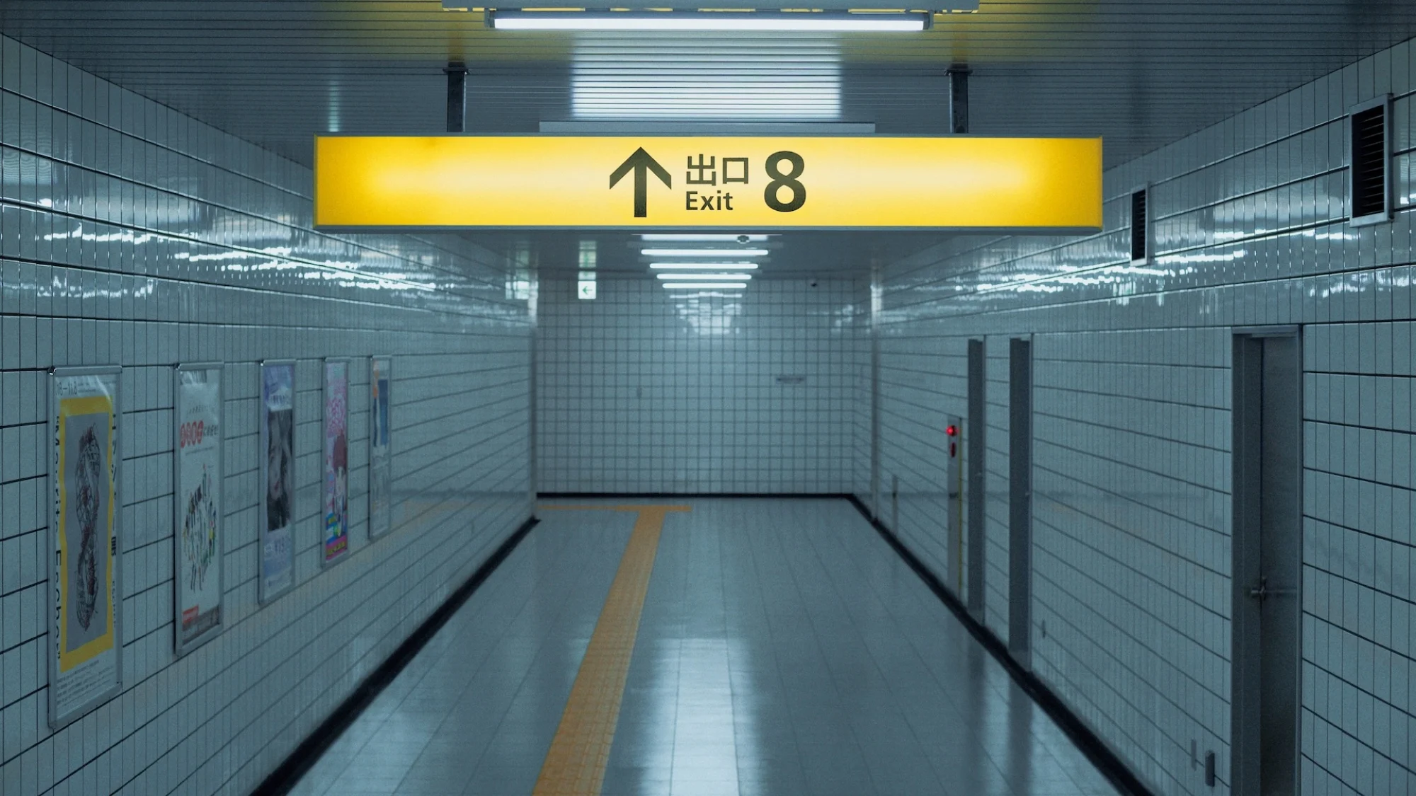 An empty subway hallway with a bright yellow sign reading "Exit 8".