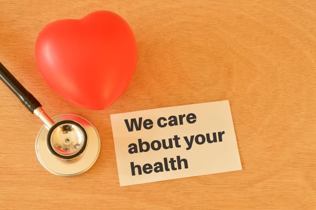 Stethoscope, red heart shape and white paper with text WE CARE ABOUT YOUR HEALTH.