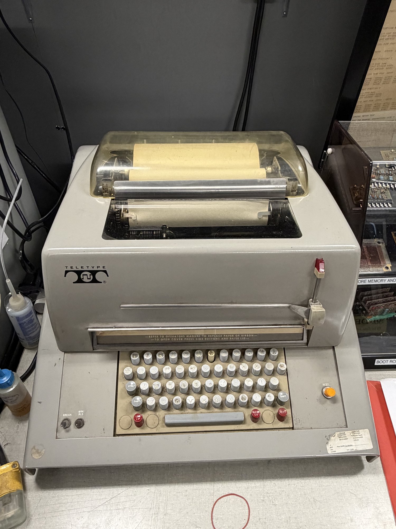 Model 35 Teletype с крышкой от пыли, рулоном бумаги и клавиатурой A Model 35 Teletype with its dust cover, paper spool, and keyboard.