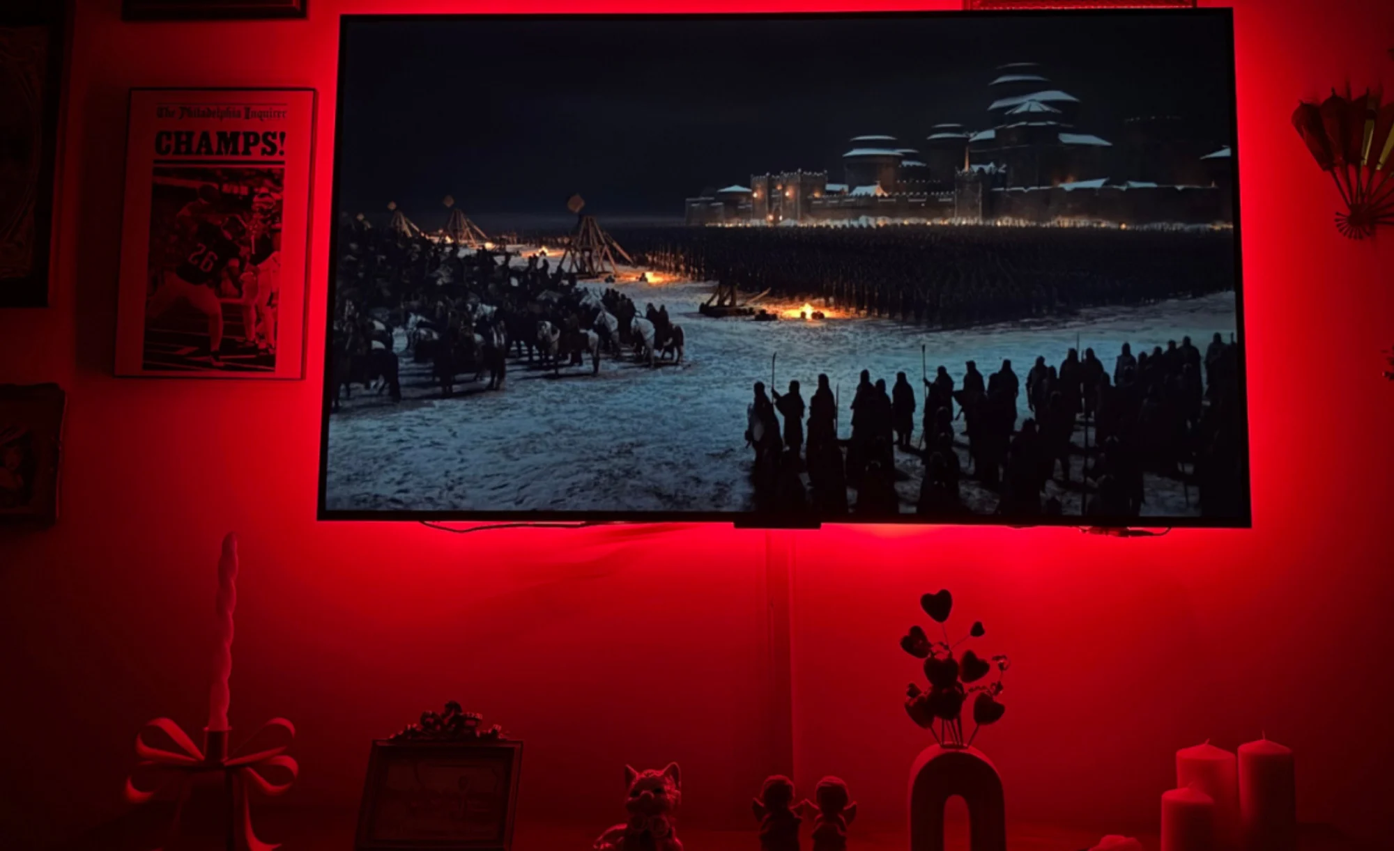 TCL QM6K TV playing "Game of Thrones" on screen while hanging on wall in front of red light