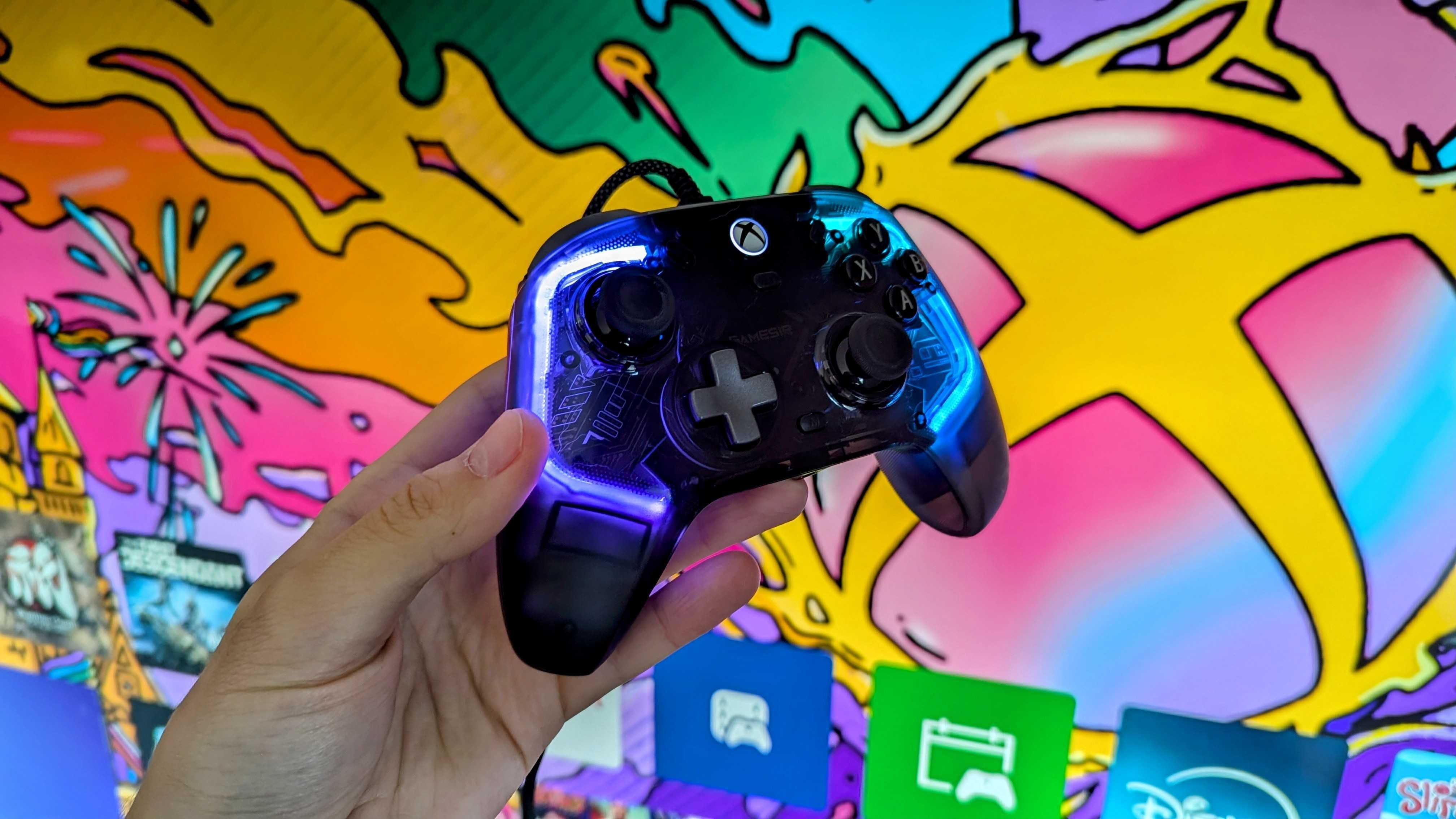 A hand holds the GameSir Kaleid Controller for Xbox, glowing with blue lighting against a vibrant, colorful gaming-themed background featuring abstract designs.