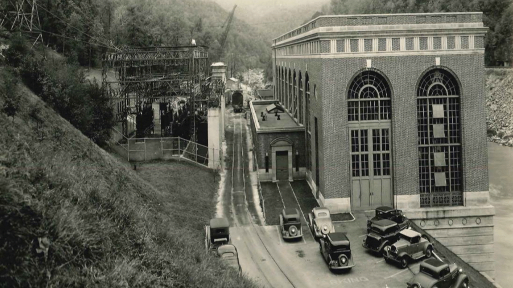 A black-and-white photo of a building with old-time cars parked in front.