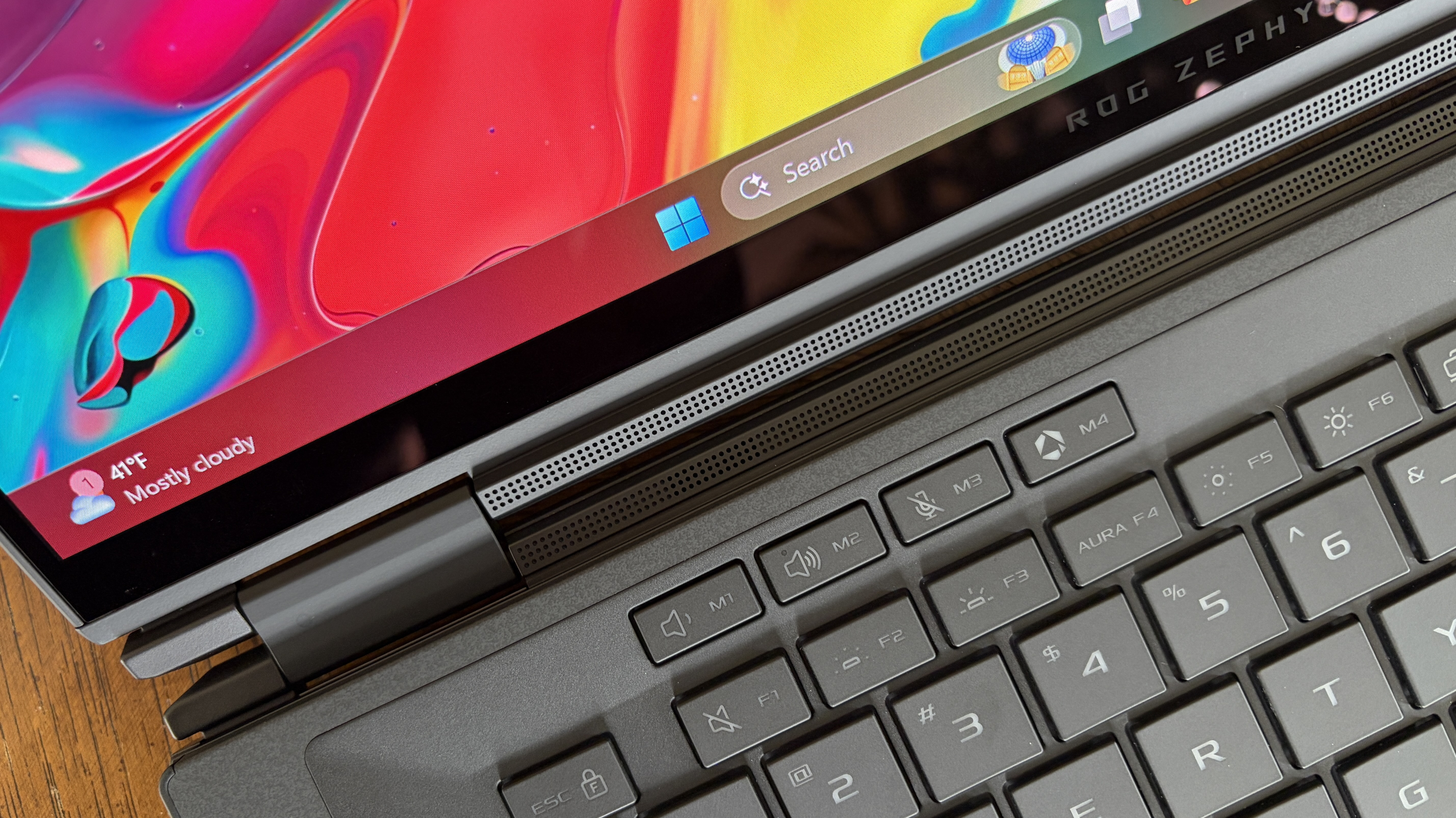 A close-up of a laptop displaying a colorful screen with swirling colors. The keyboard and part of the metal hinge are visible. The taskbar shows a partly cloudy weather icon and a temperature of 41&deg;F. The overall tone is vibrant and modern.