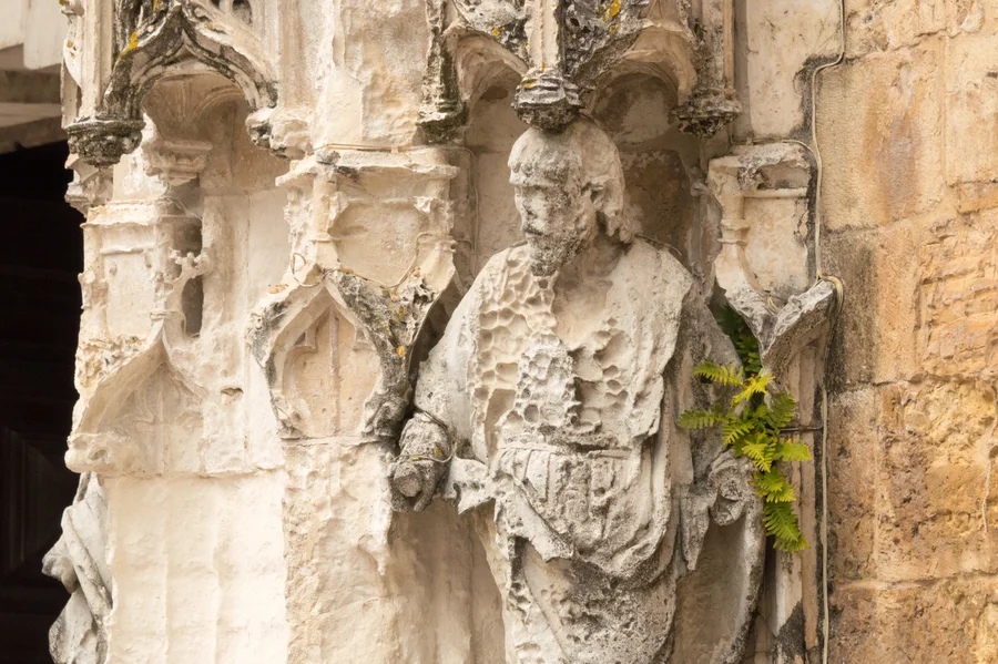 Ornate white stonework with a statue showing a person with visible pockmarks