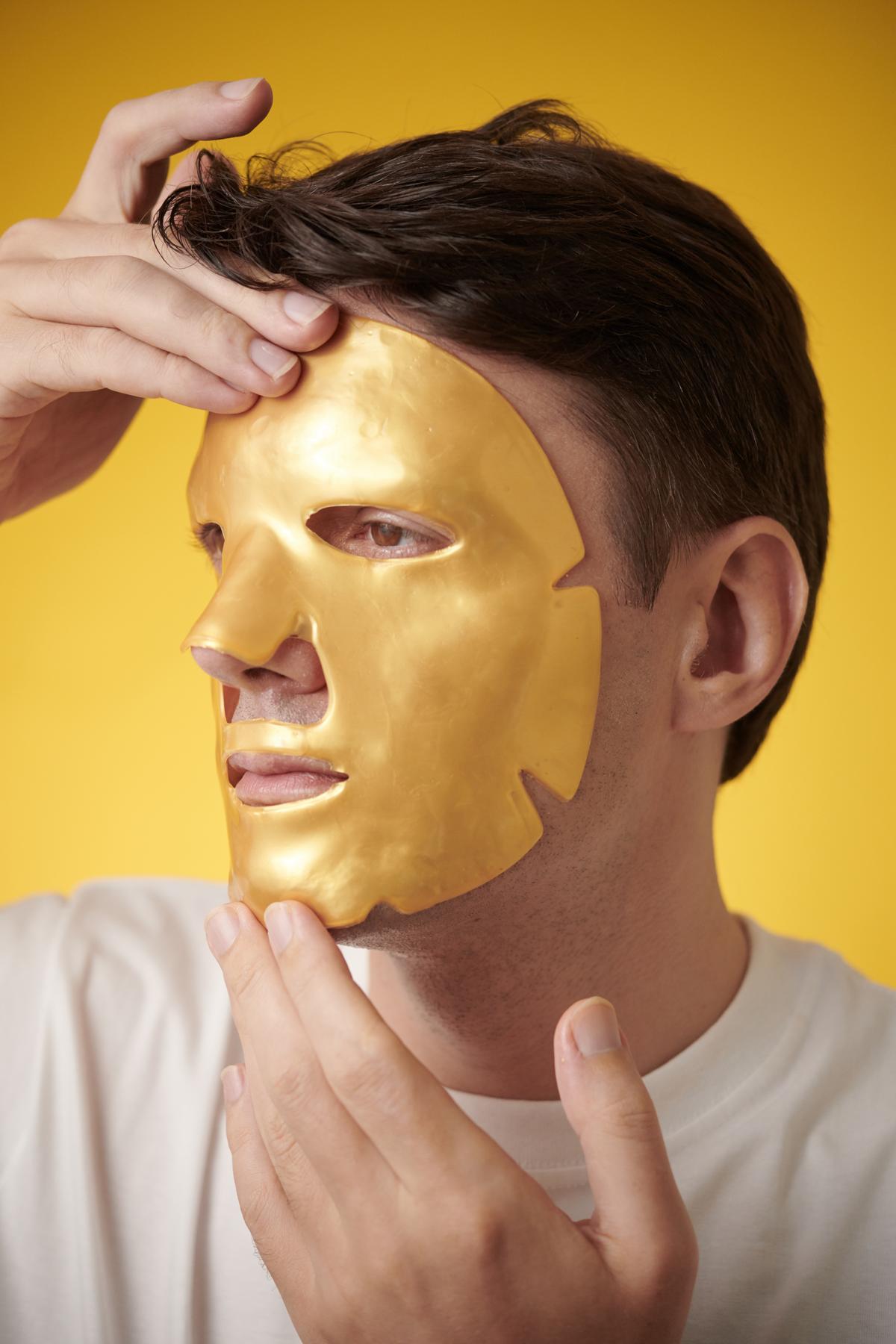 Mature man applying hydrogel face mask to soothe skin after treatment