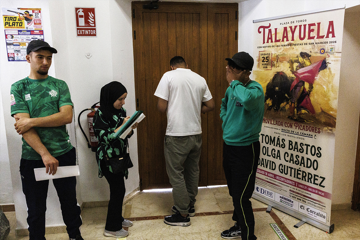 Cuatro inmigrantes esperan su turno para tramitar la documentación en el Ayuntamiento de Talayuela (Cáceres) con la que regularizar su situación en España.