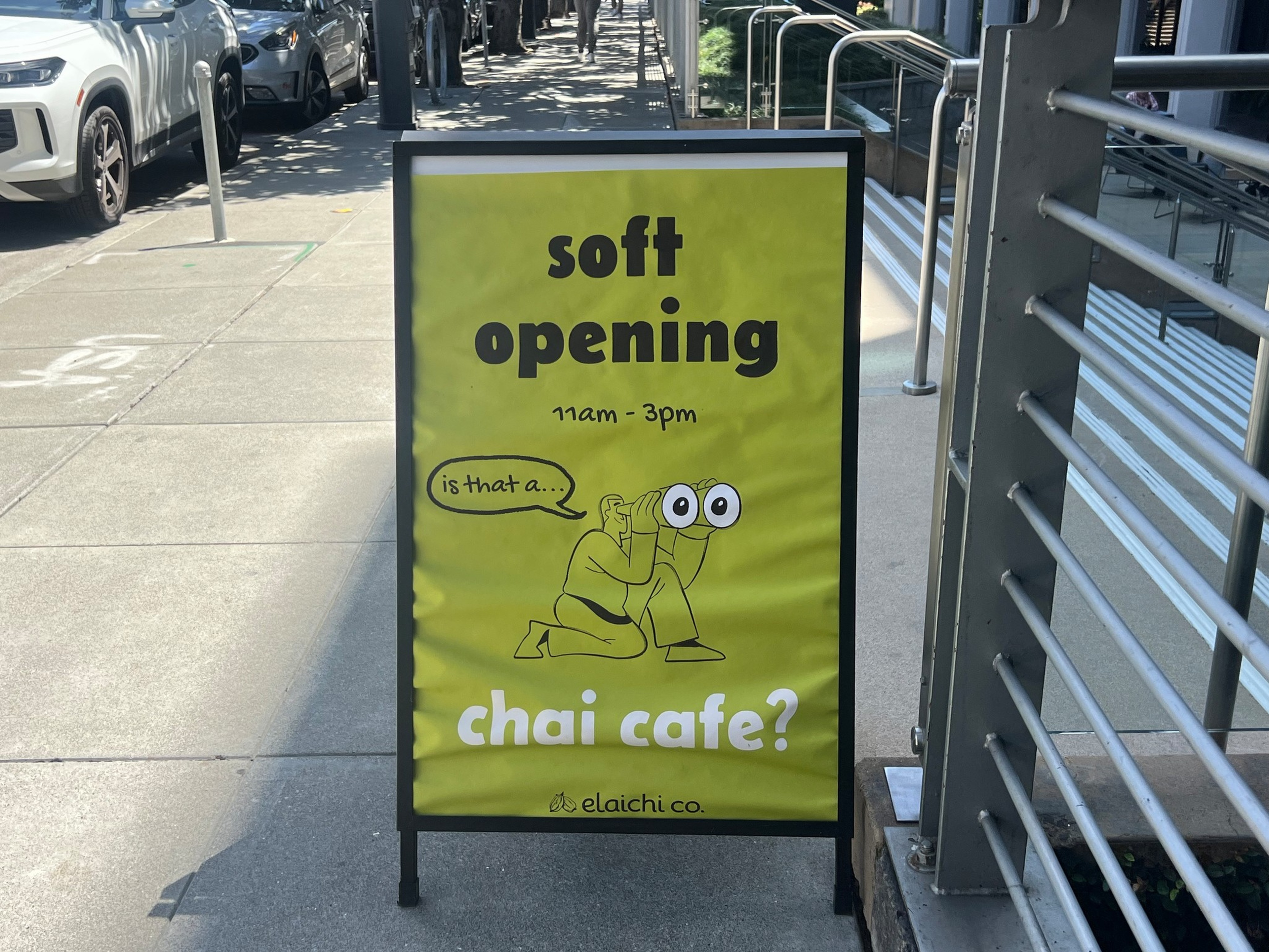 Soft opening announcement for chai cafe from 11am to 3pm with a cartoon person using binoculars asking, “is that a… chai cafe?” on a yellow background.