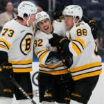 Boston Bruins' Marat Khusnutdinov (92) celebrates with David Pastrnak (88) and Charlie McAvoy (73) after scoring a goal during the third period of an NHL hockey game against the New York Islanders Tuesday, Nov. 4, 2025, at UBS Arena in Elmont, N.Y.
