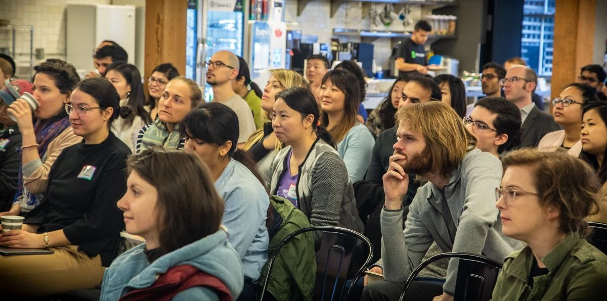 A large audience listening intently while looking ahead