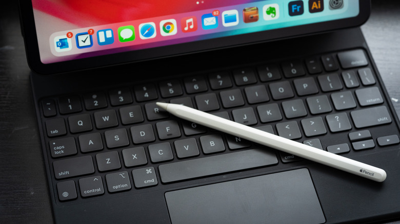 An Apple Pencil on top of a Magic Keyboard with an iPad.