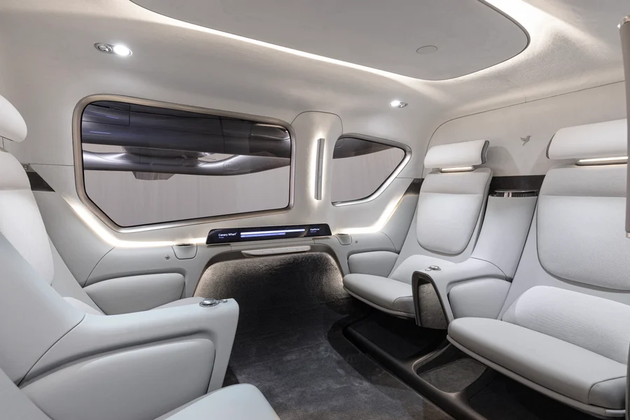 The Valo cabin interior has four light-colored passenger seats, large windows and soft lighting.