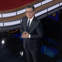 Stephen Colbert holds his hands in prayer while hosting "The Late Show."