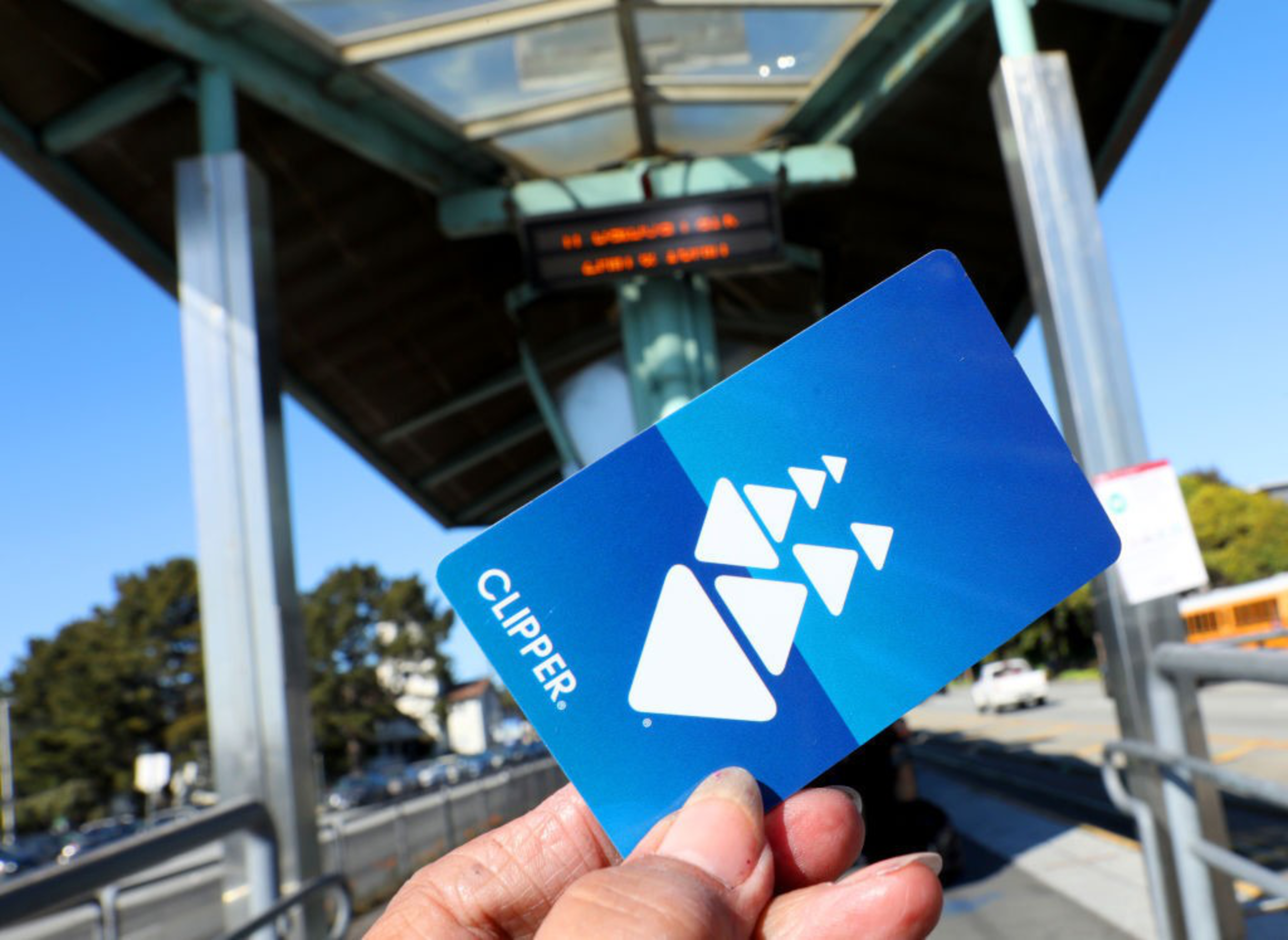 A person’s hand holds a bright blue plastic card with white shapes on it in the outline of a clipper ship.