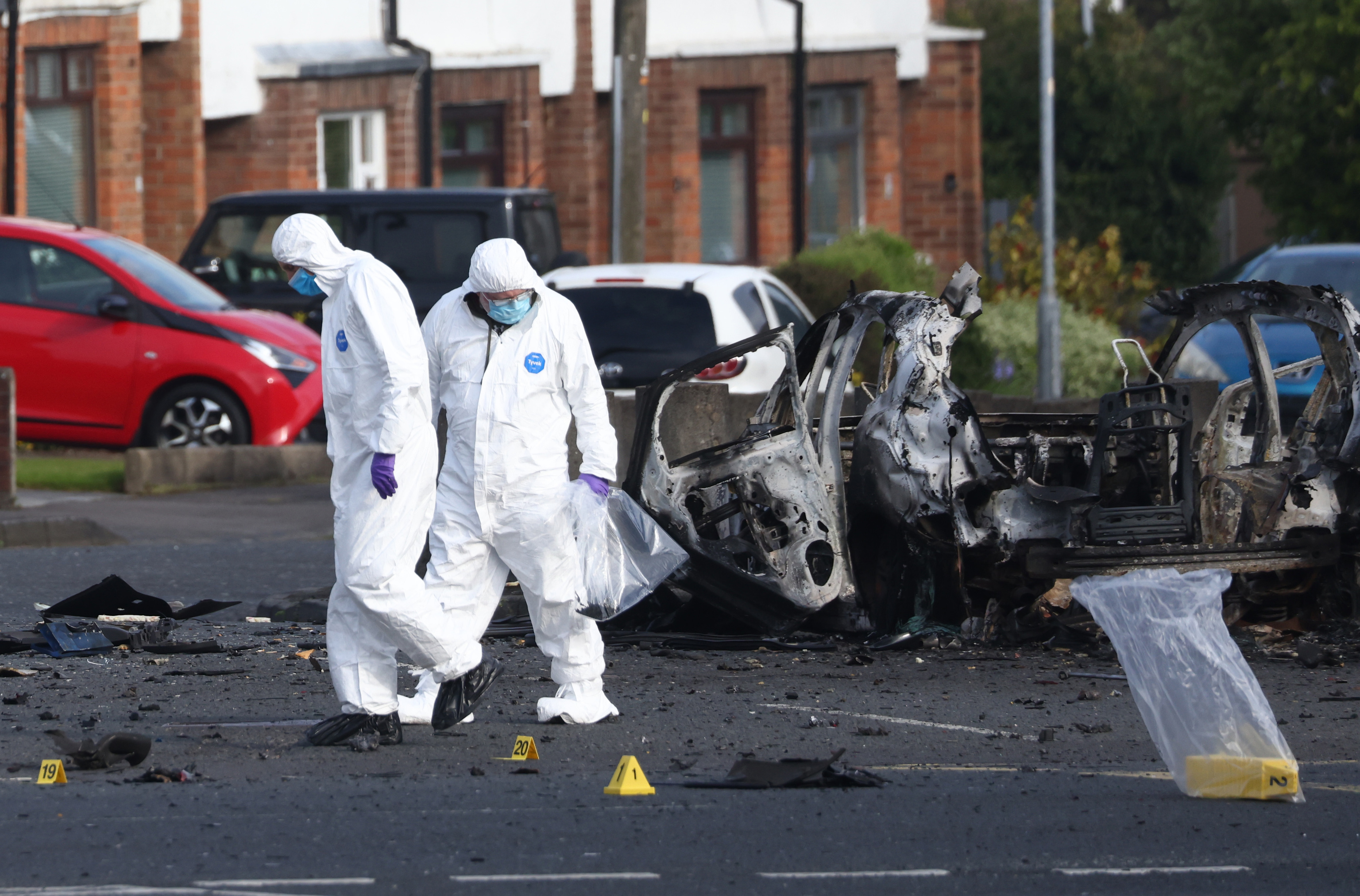 Investigadores forenses inspeccionan el lugar donde estall� un coche bomba en Dunmurry, al sur de Belfast.