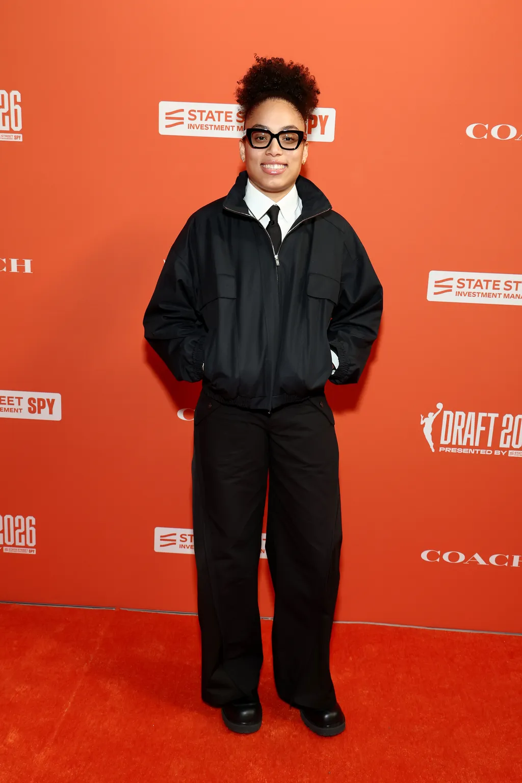 Image may contain Fashion Adult Person Clothing Coat Jacket Accessories Glasses Formal Wear Suit and Standing