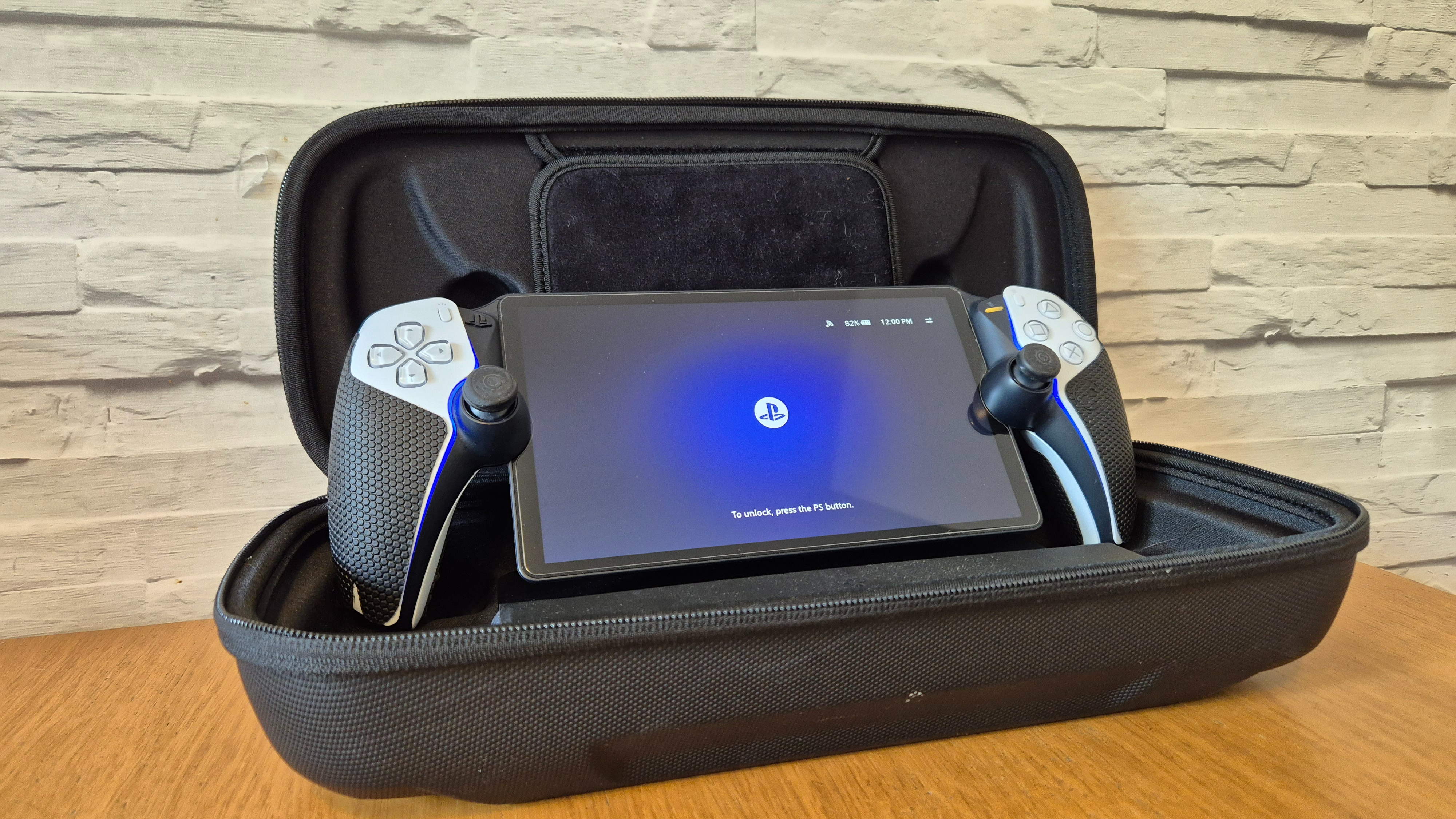 The Spigen Rugged Armor Pro case for PlayStation Portal sitting on a wooden surface infront of a white brick-effect wall with a PlayStation Portal sitting within it.